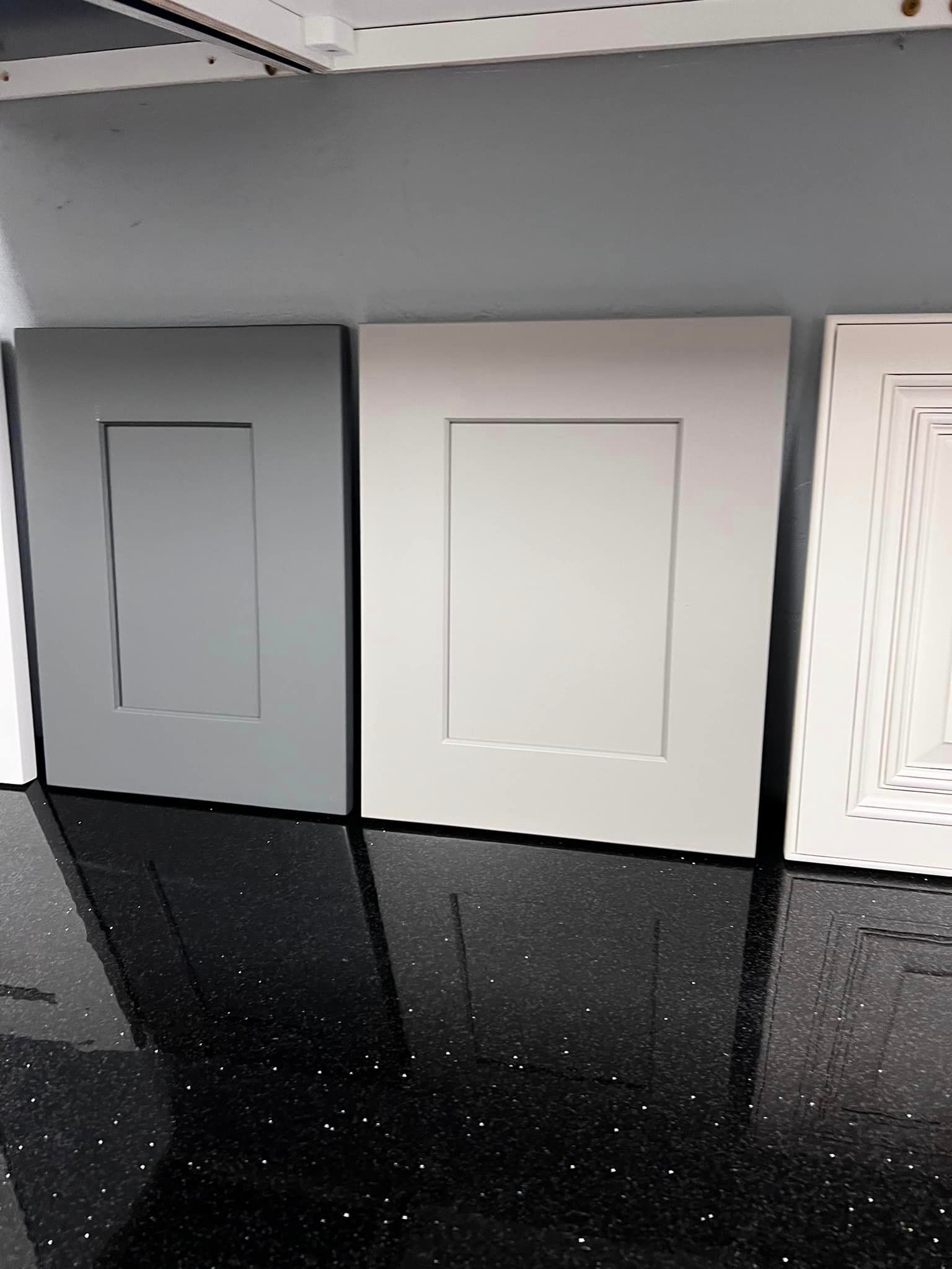 Three cabinet doors are sitting on top of a black counter.