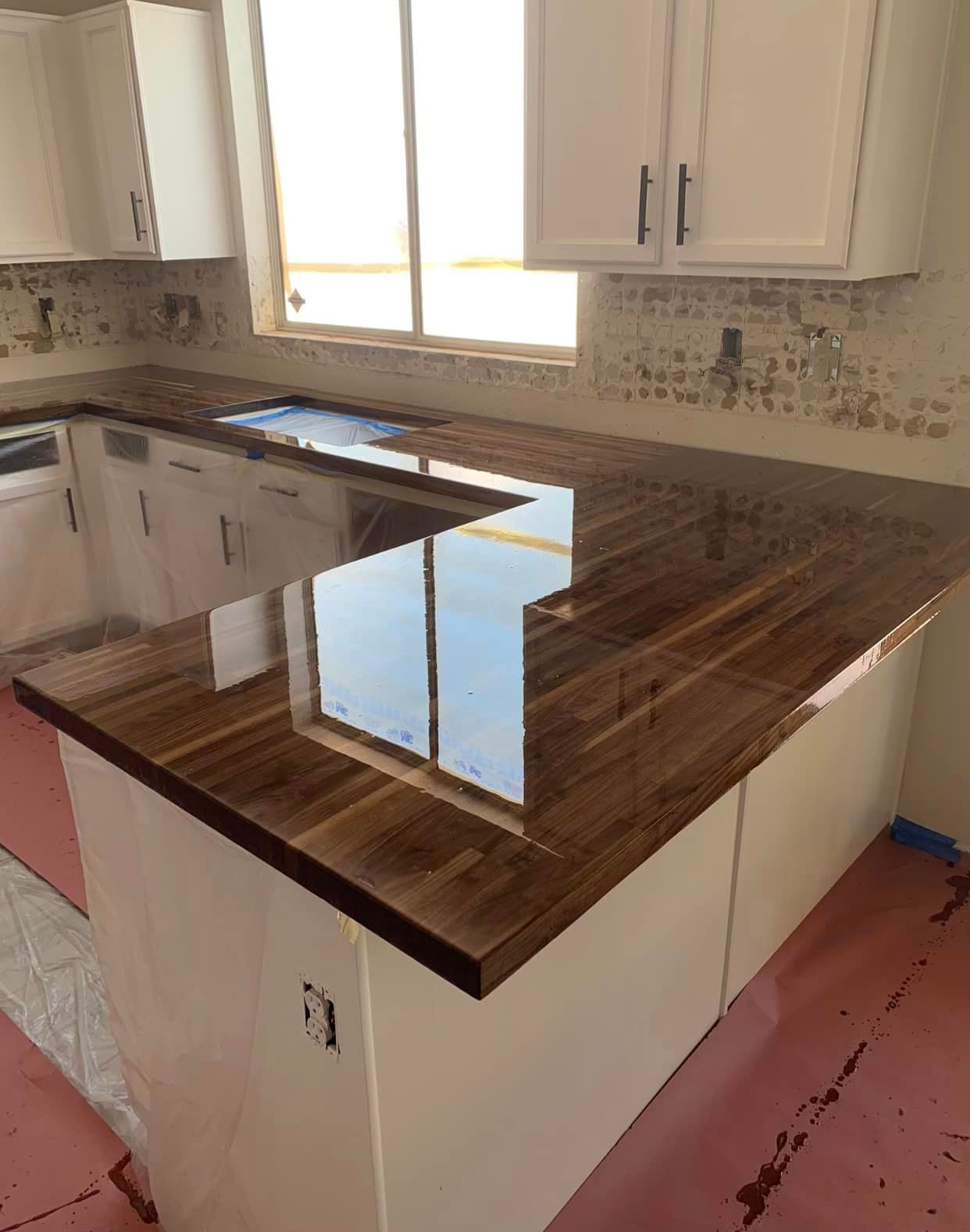 A kitchen with a wooden counter top and white cabinets.