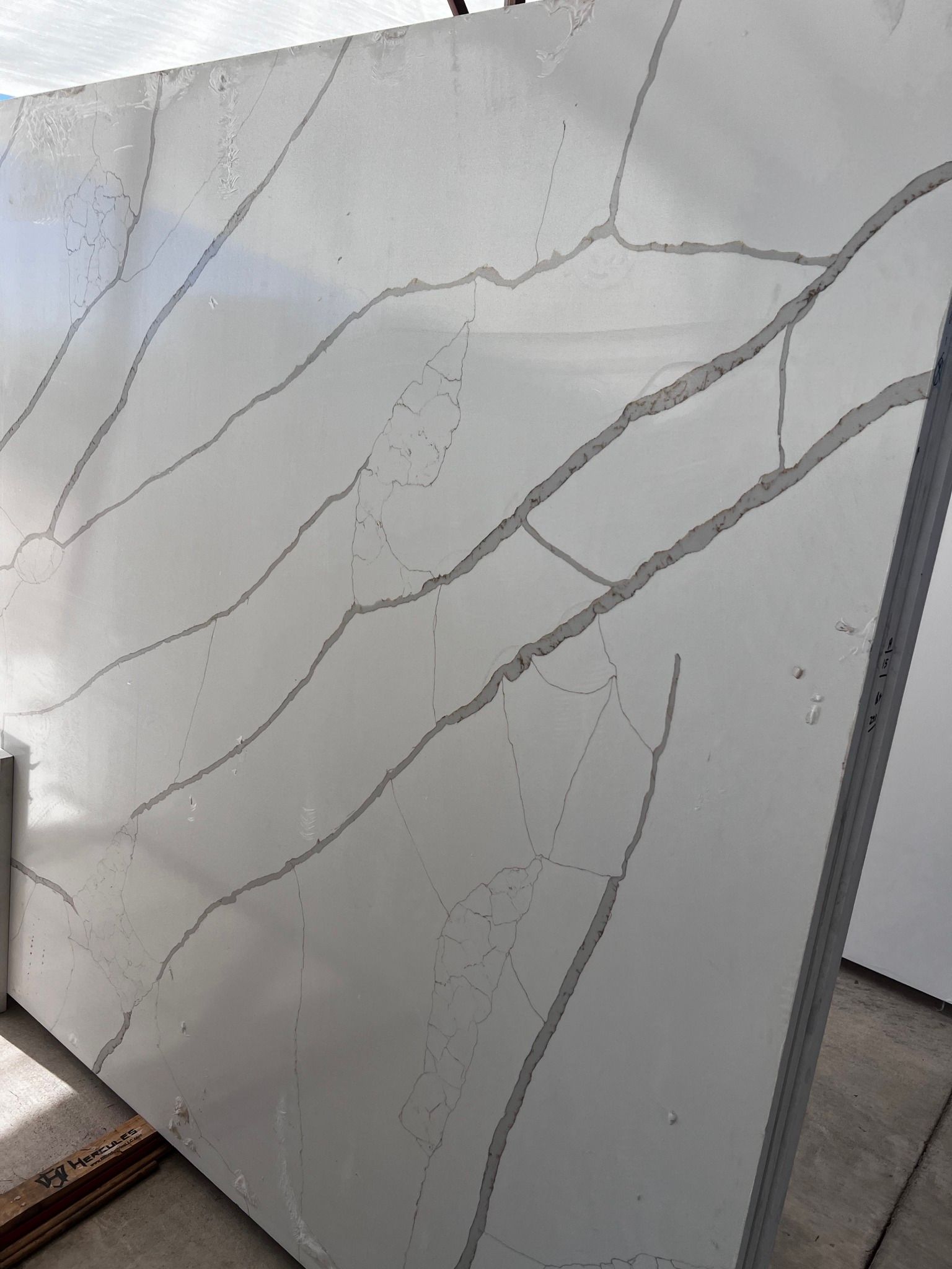 A white granite slab with a gray stripe on it is sitting on the ground.