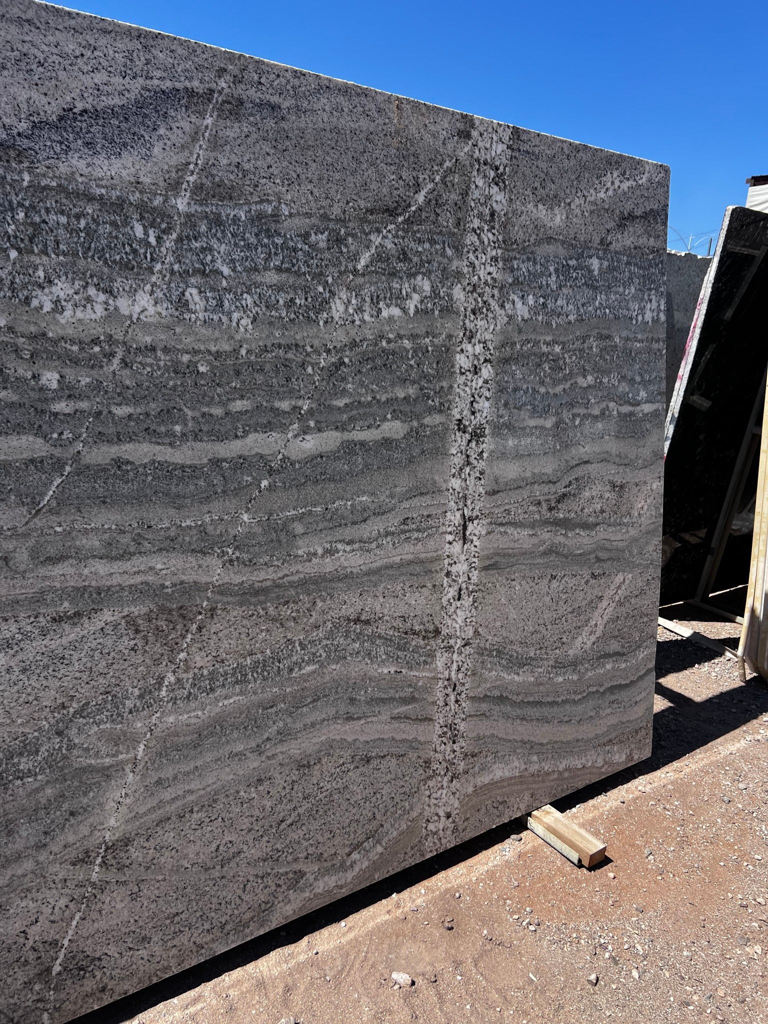 A large piece of granite is sitting on the ground next to a wall.