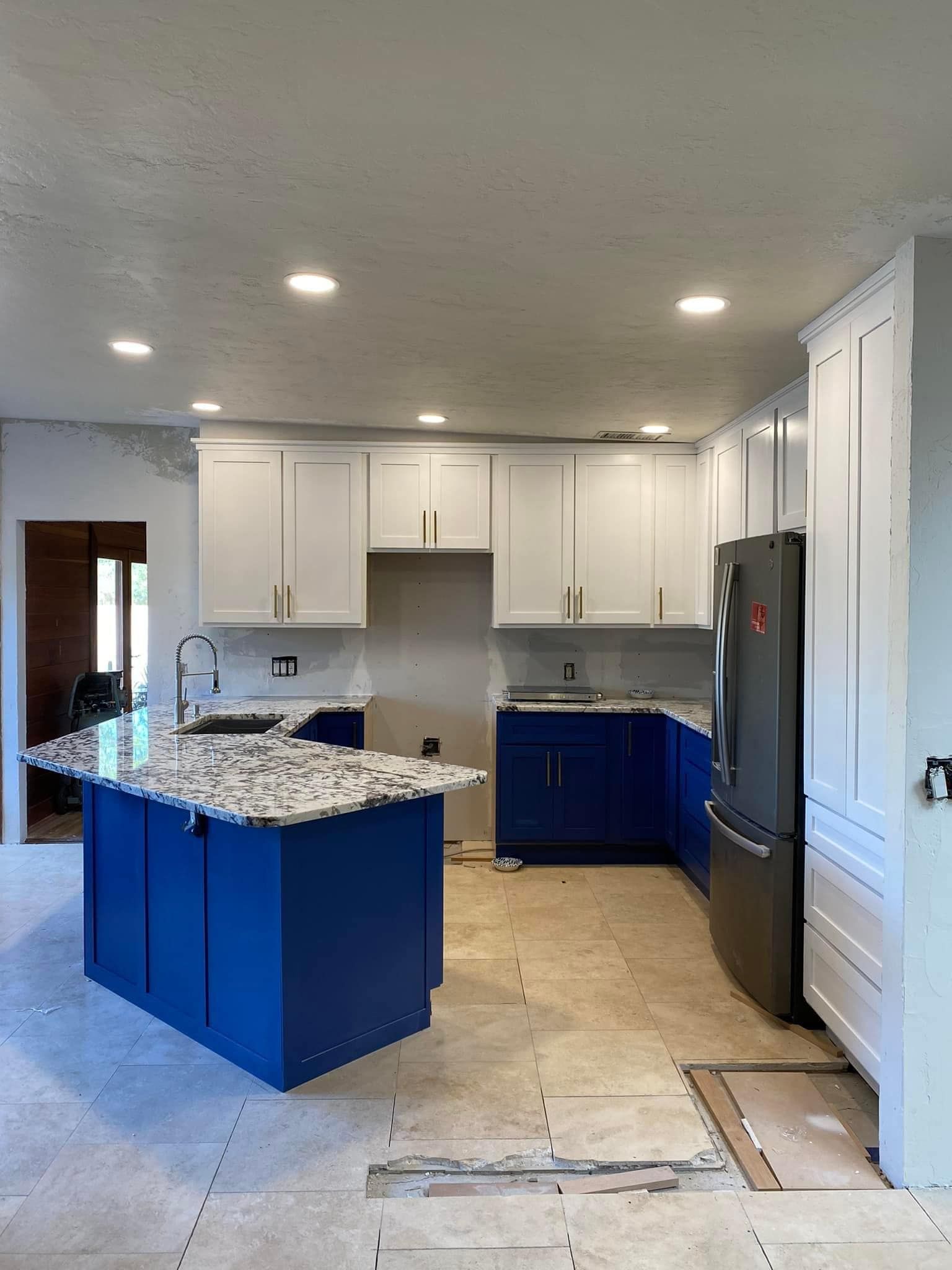 A kitchen with blue cabinets and granite counter tops is being remodeled.