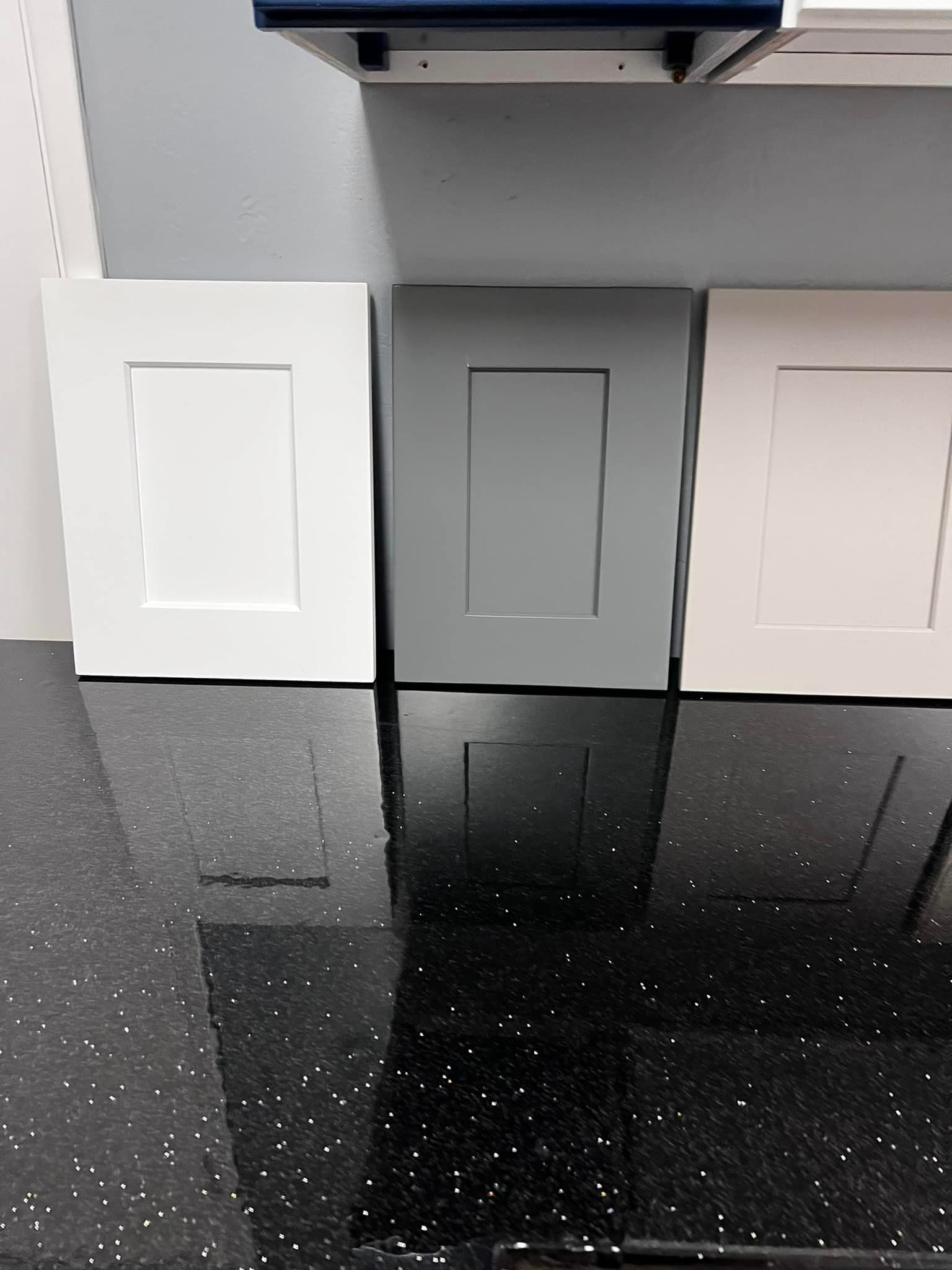 Three cabinet doors are sitting on top of a black counter.