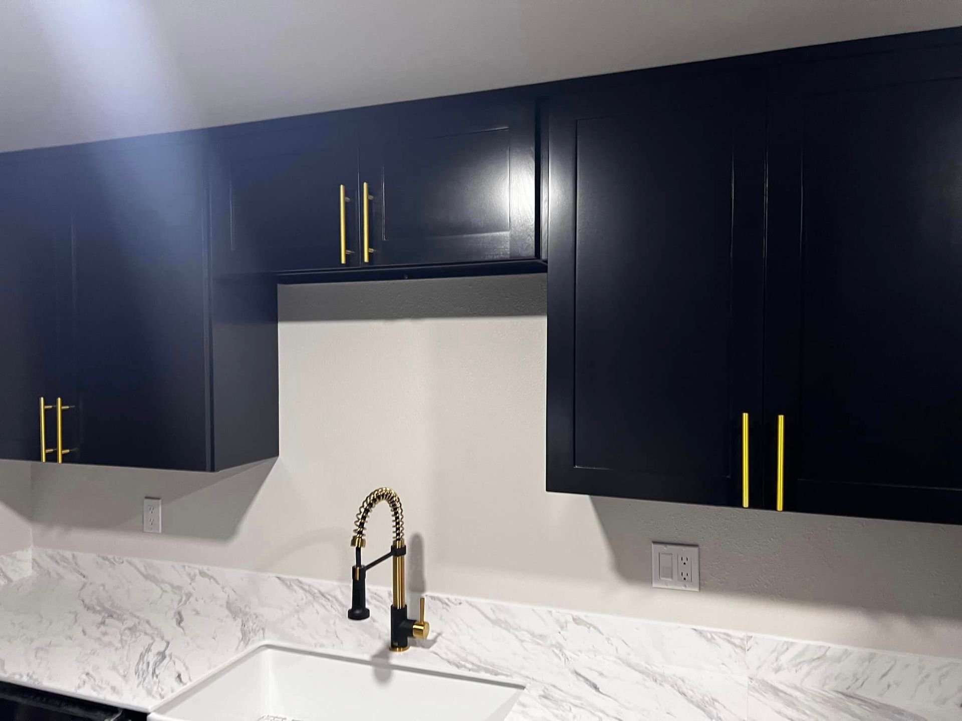 A kitchen with black cabinets and a white sink.