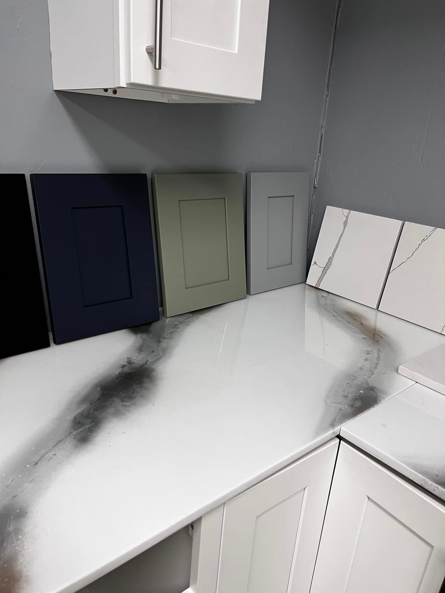 A kitchen with white cabinets and a white counter top.