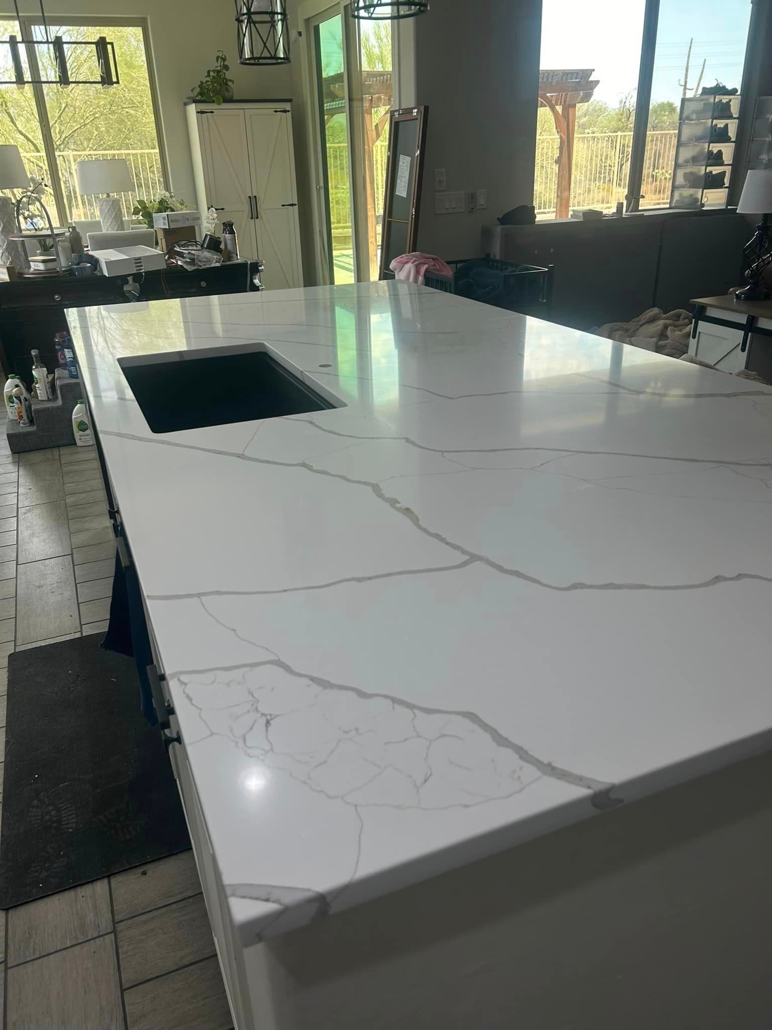 A kitchen with a large white counter top and a sink.