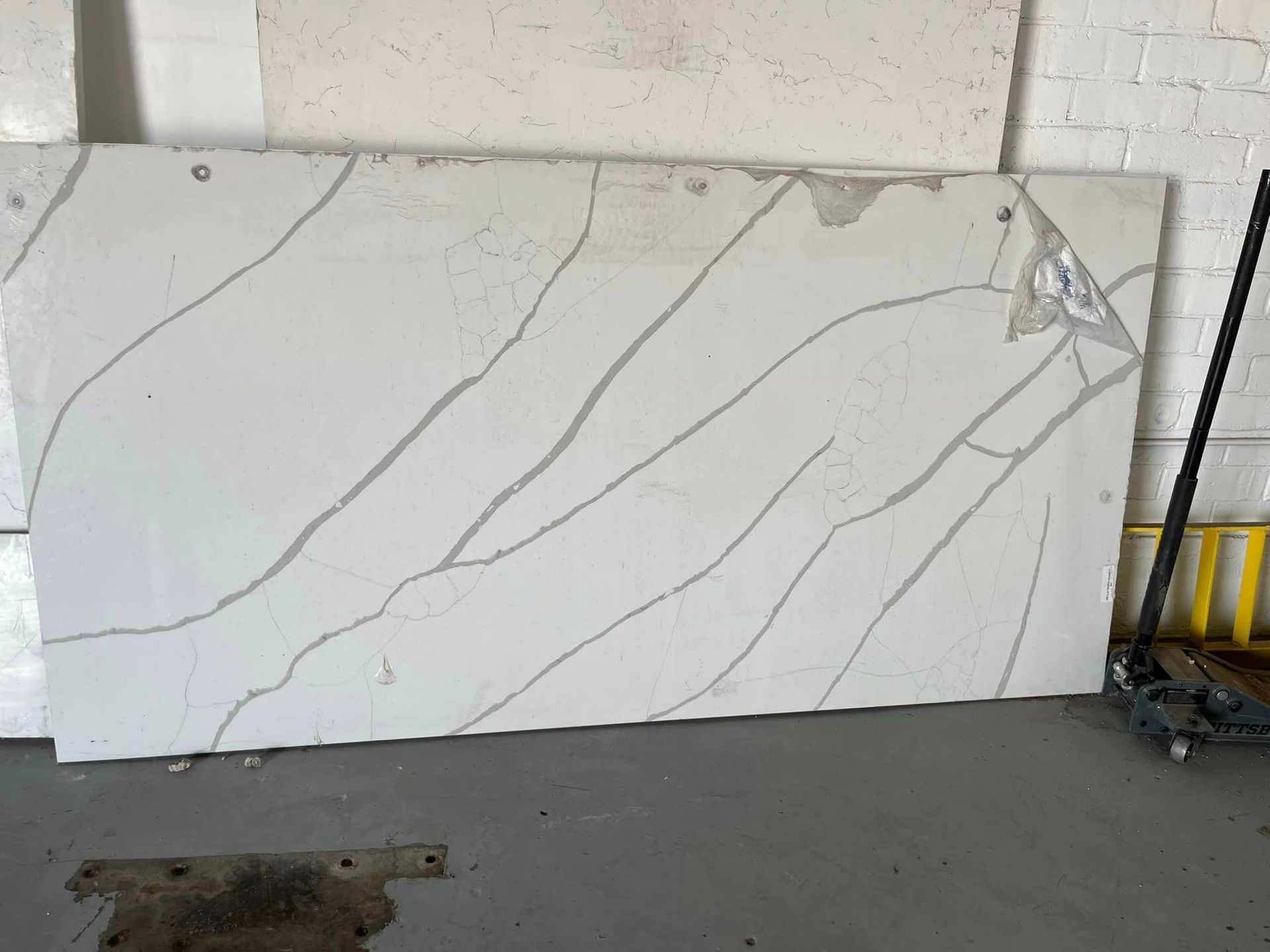 A large piece of white marble is sitting on the floor next to a mop.