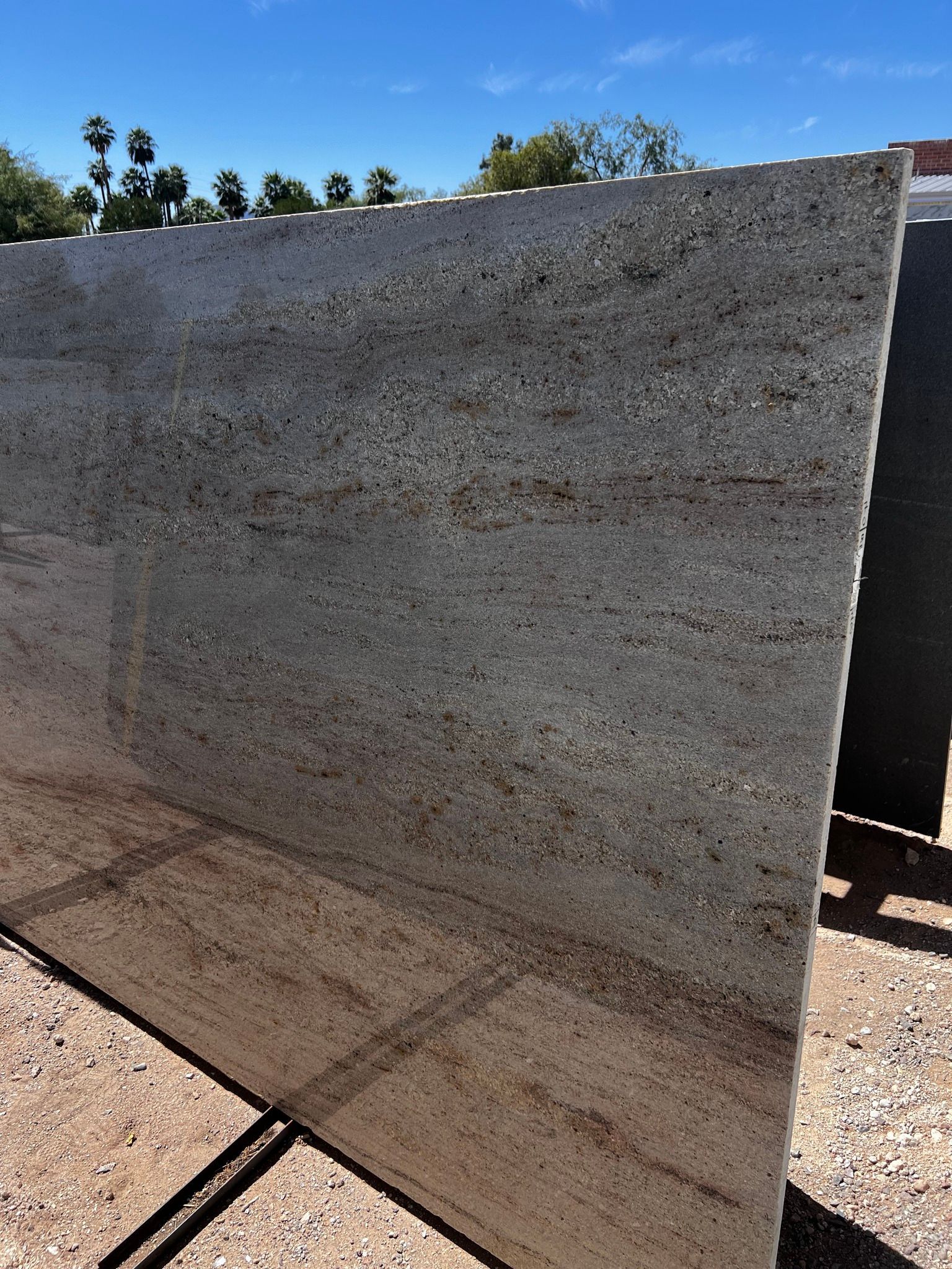 A large granite slab is sitting on top of a gravel road.