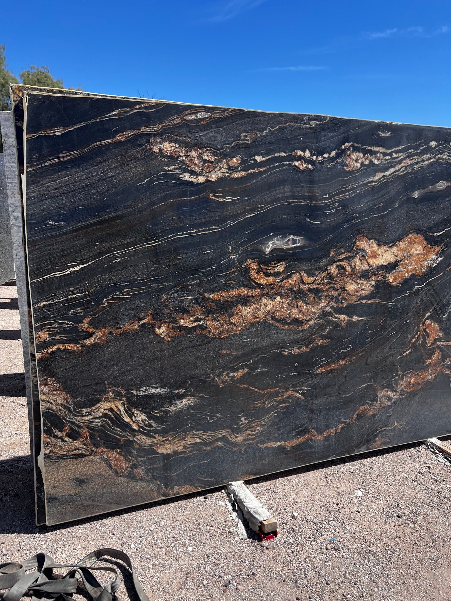 A large black granite slab is sitting on top of a pile of gravel.
