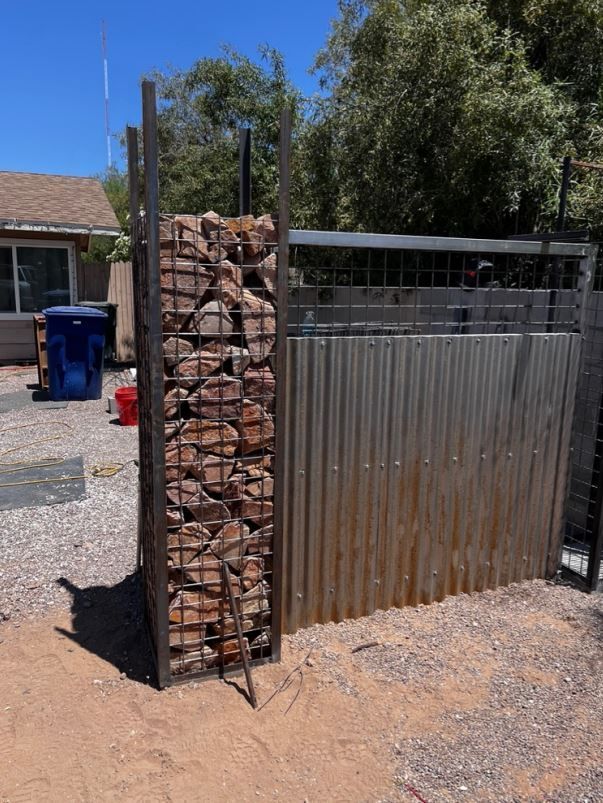A metal fence with a pile of rocks behind it
