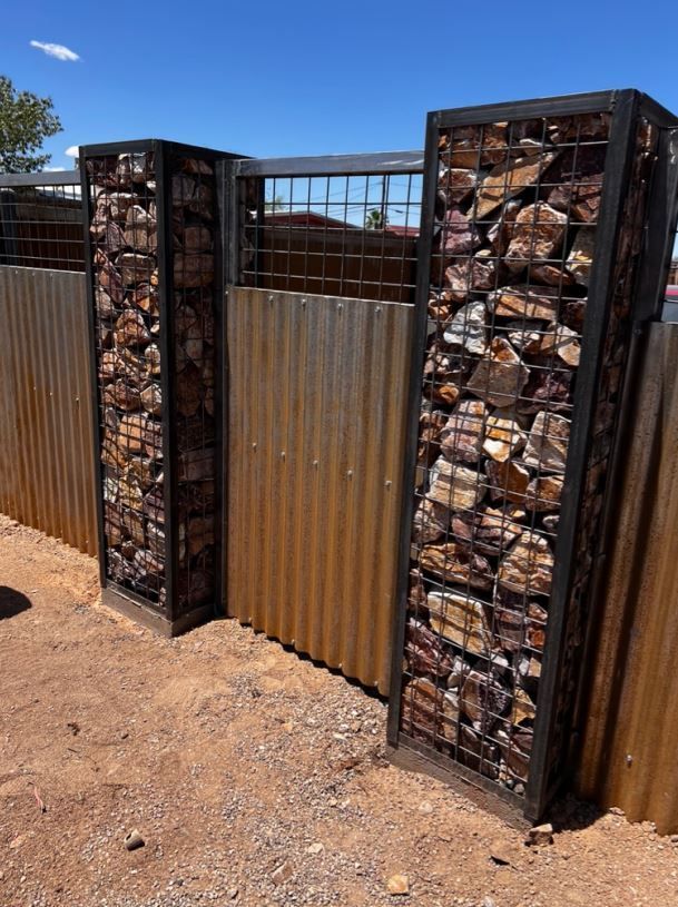 A metal fence with two pillars made of rocks