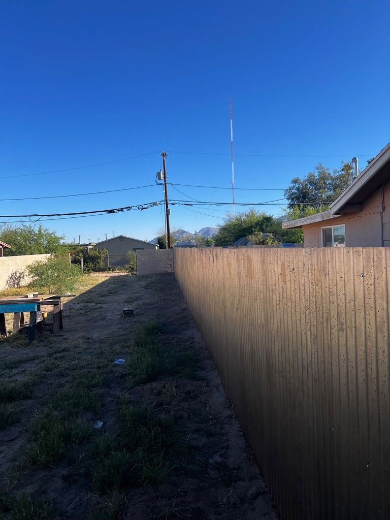 A wooden fence surrounds a backyard with a house in the background.