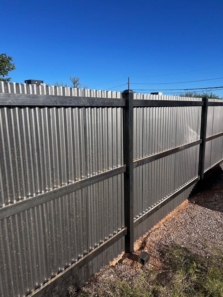 A close up of a metal fence with a blue sky in the background.