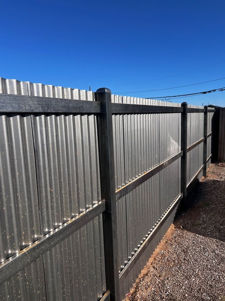 A metal fence with wooden posts and a blue sky in the background