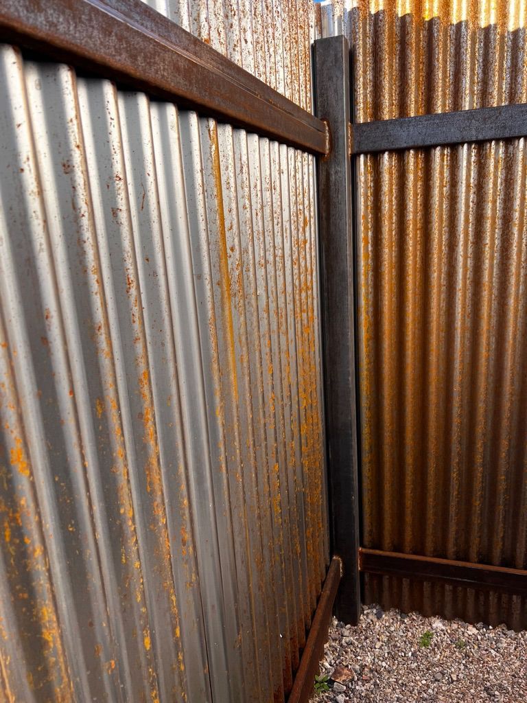 A rusty metal fence with a wooden frame