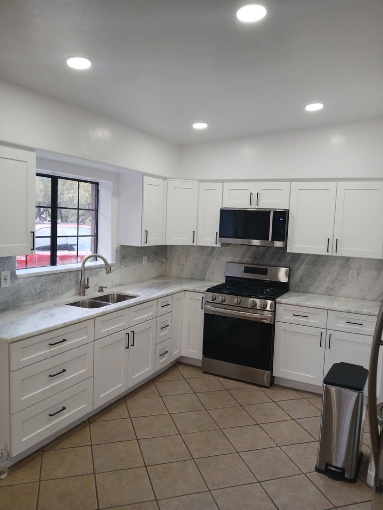 White kitchen with white cabinets, a stainless steel range, and grey countertops.
