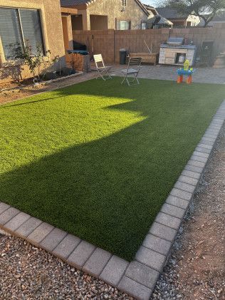A backyard with a lot of grass and a brick walkway.