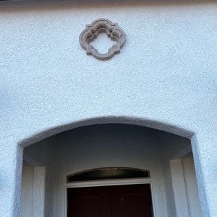 A white house with a red door and a white archway.