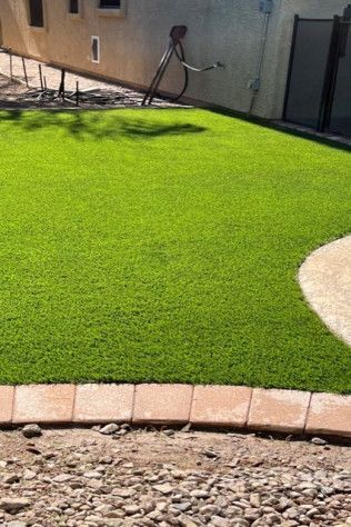 A lush green lawn with a brick border in front of a house.