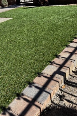 A brick walkway leading to a lush green lawn.