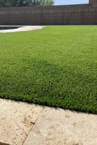A lush green lawn with a pool in the background.