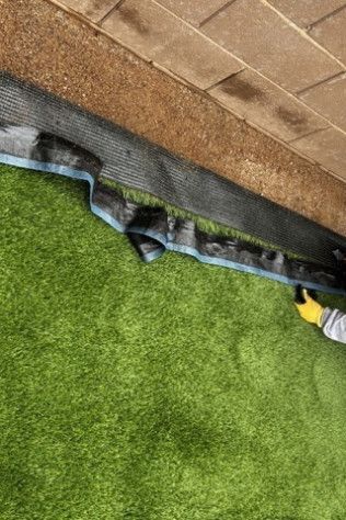A person is installing artificial grass on a patio.
