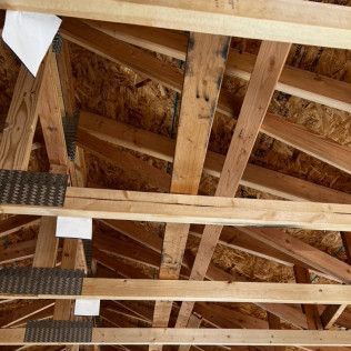 The ceiling of a house under construction is made of wooden beams.