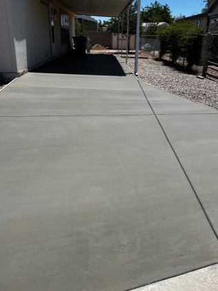 A concrete driveway with a canopy over it in front of a house.