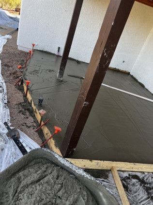 A concrete floor is being poured on a porch.
