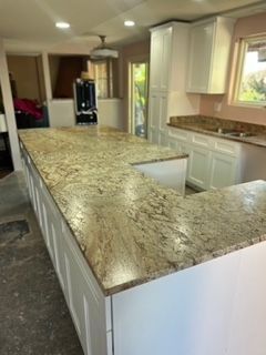 A large, light granite countertop on a white kitchen island and cabinets. 