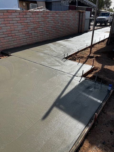 A sidewalk is being built next to a brick wall.