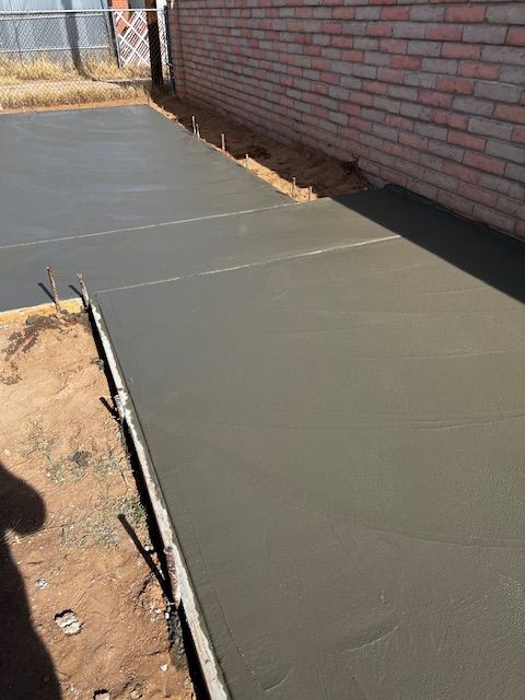 A concrete walkway is being built in front of a brick building.