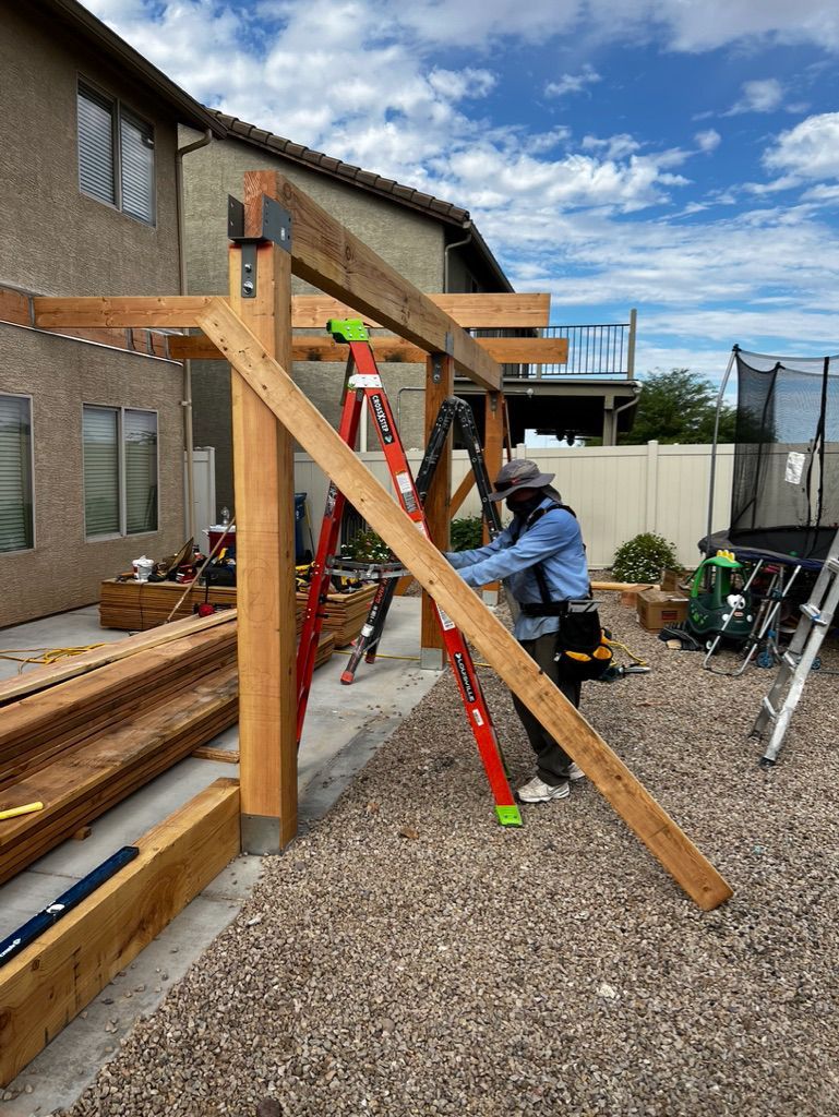 A man is standing on a ladder working on a wooden structure.