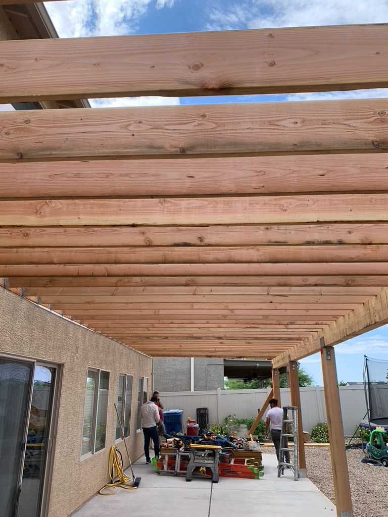A group of people are working on a wooden pergola.