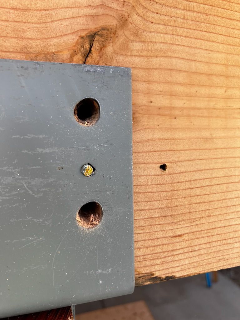 A piece of metal with two holes in it is attached to a piece of wood.