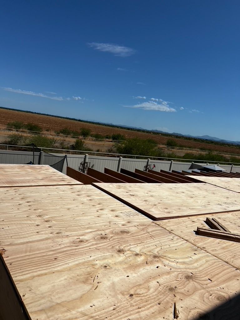 A wooden roof with a blue sky in the background is being built.
