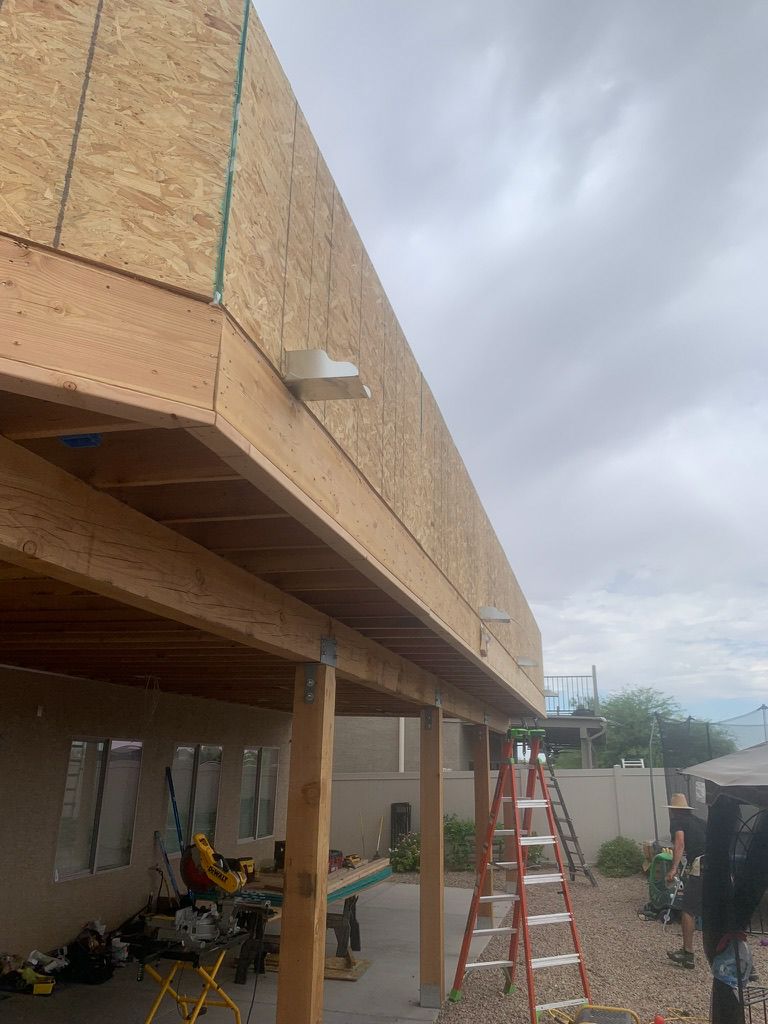 A man is standing under a wooden structure with a ladder.