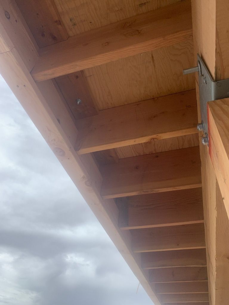 The ceiling of a building under construction with a cloudy sky in the background.
