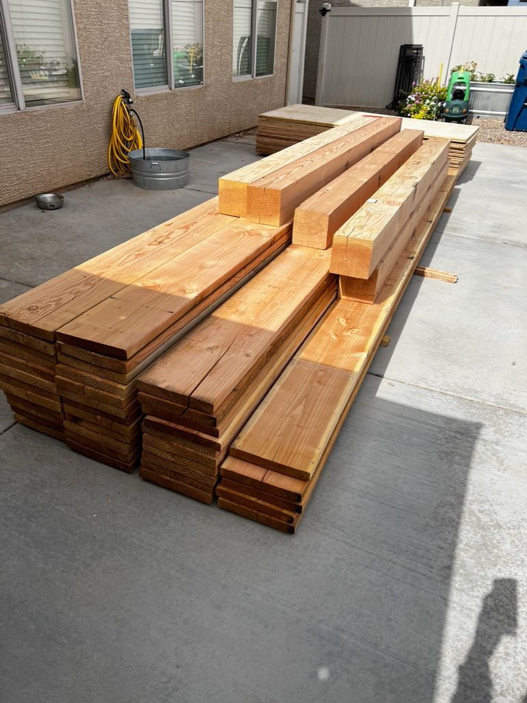 A pile of wood is sitting on the ground in a driveway.