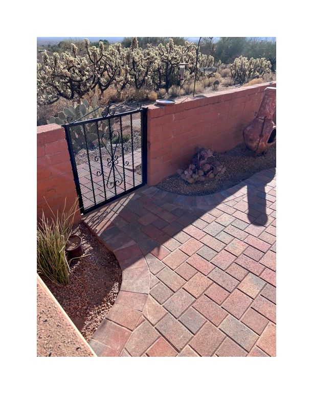 A brick walkway with a gate leading to a patio with a view of the desert.