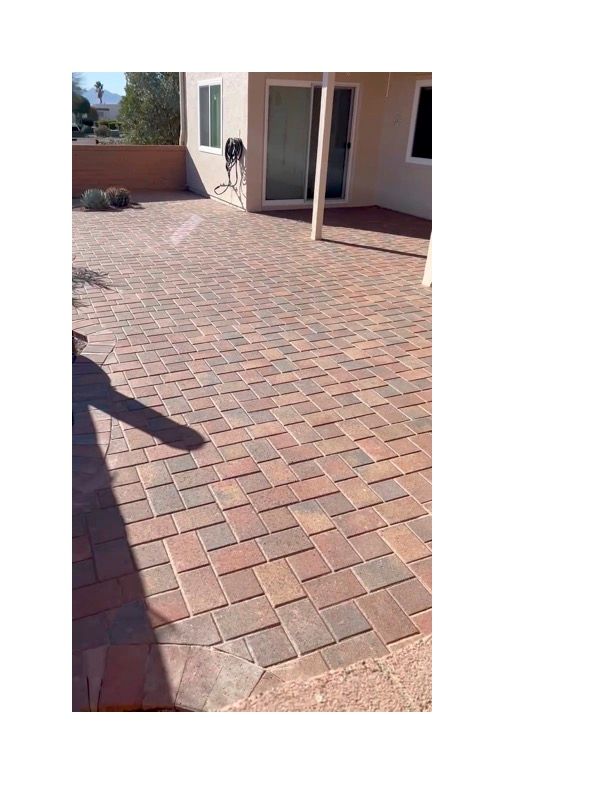 A brick patio in front of a house with a sliding glass door.