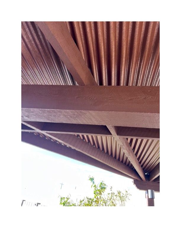 A close up of a wooden roof with a tree in the background.