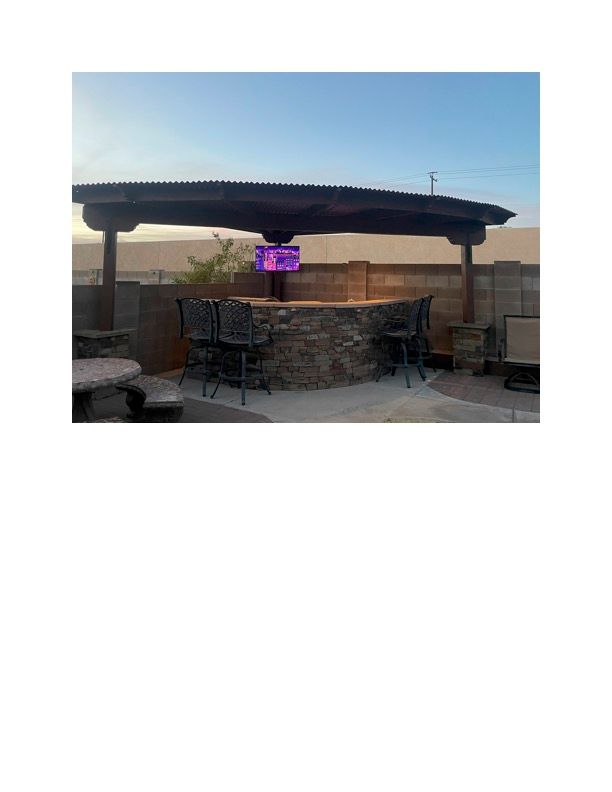 A patio with a bar , tables and chairs under a pergola.