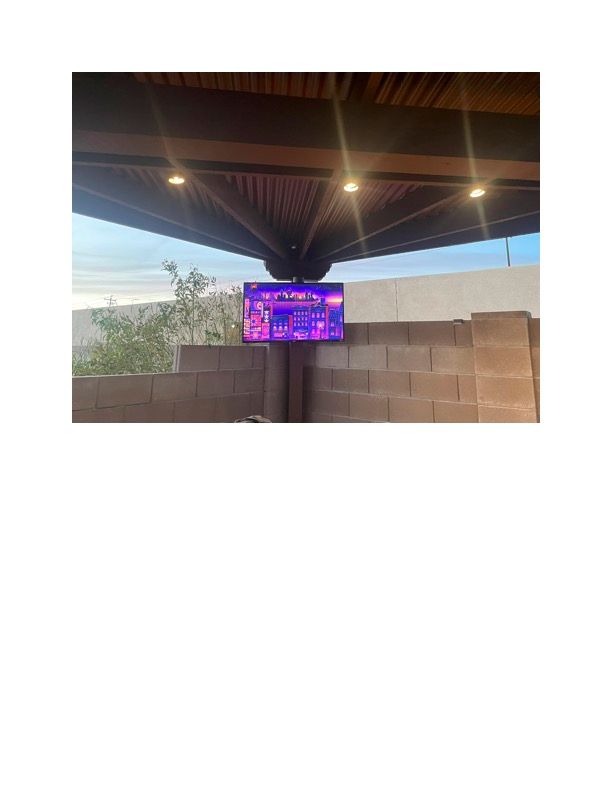 A television is hanging from the ceiling of a building.