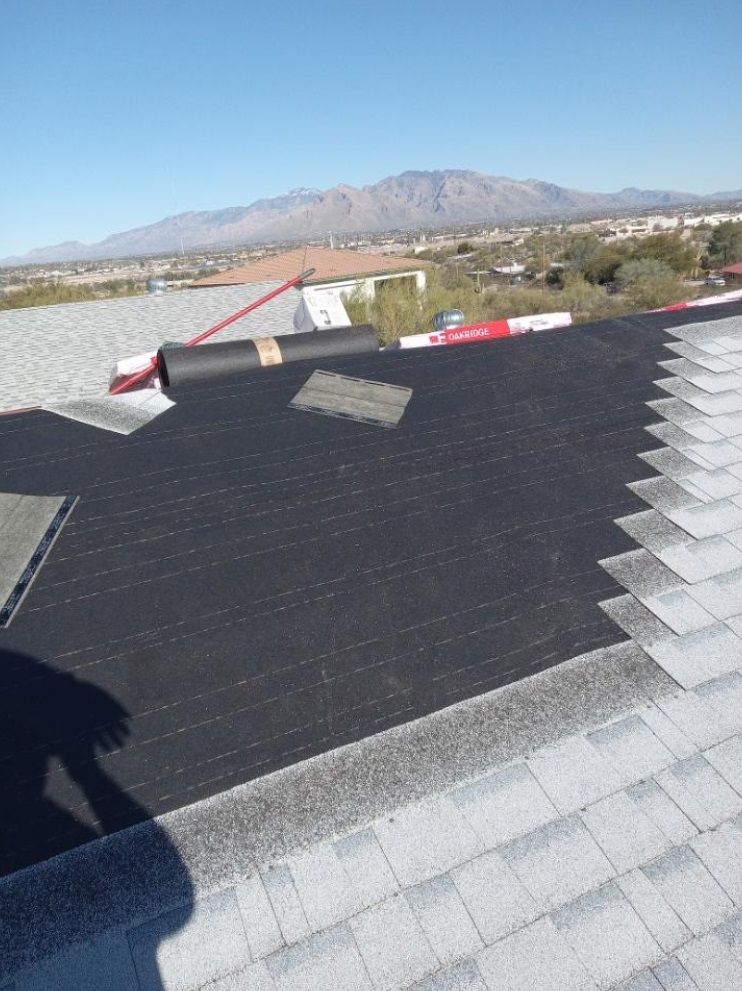 A roof with a roll of shingles on it and mountains in the background