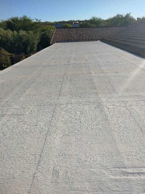 A concrete roof with trees in the background and a blue sky in the background.