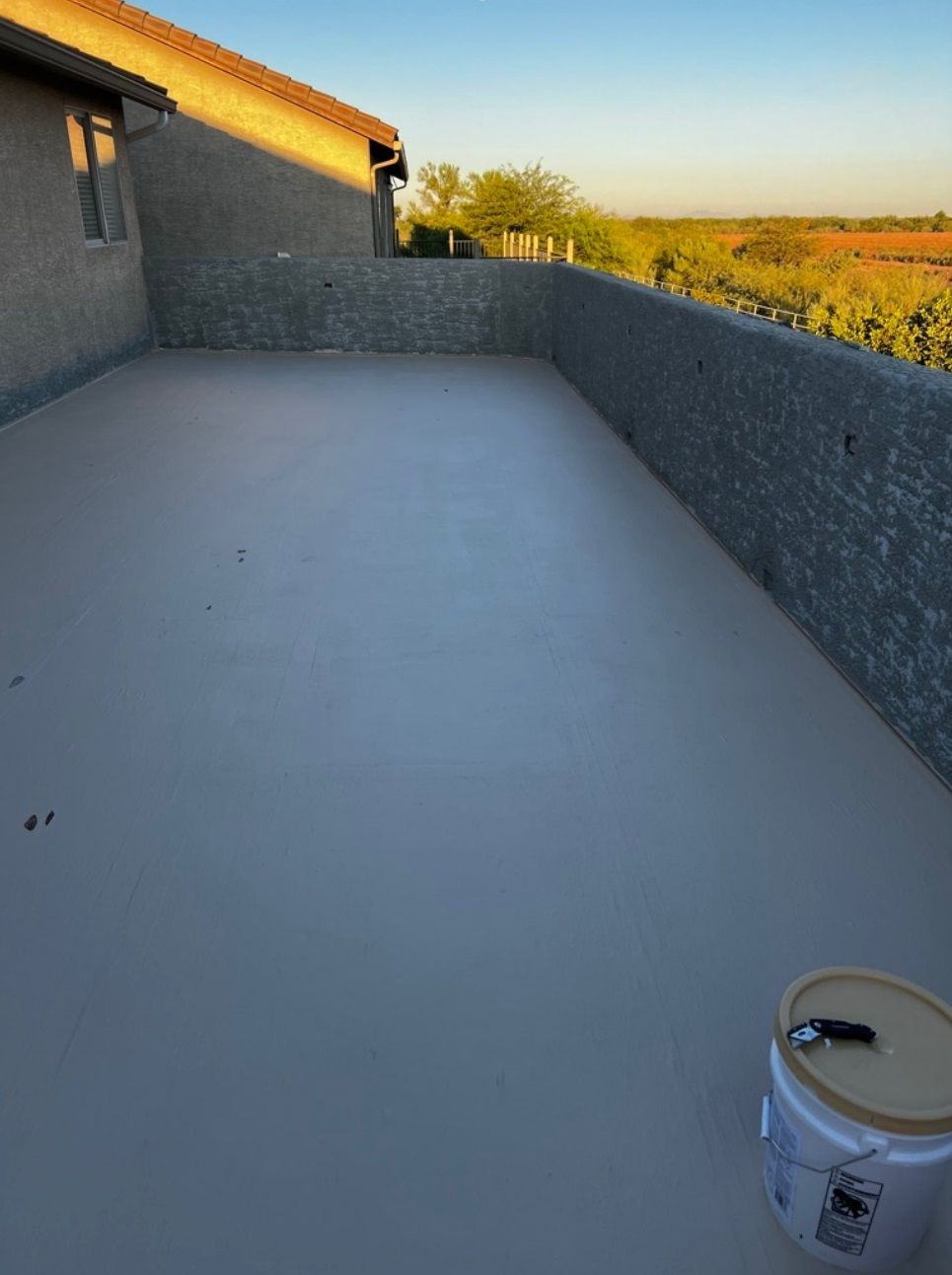 A bucket of paint sits in the middle of a patio