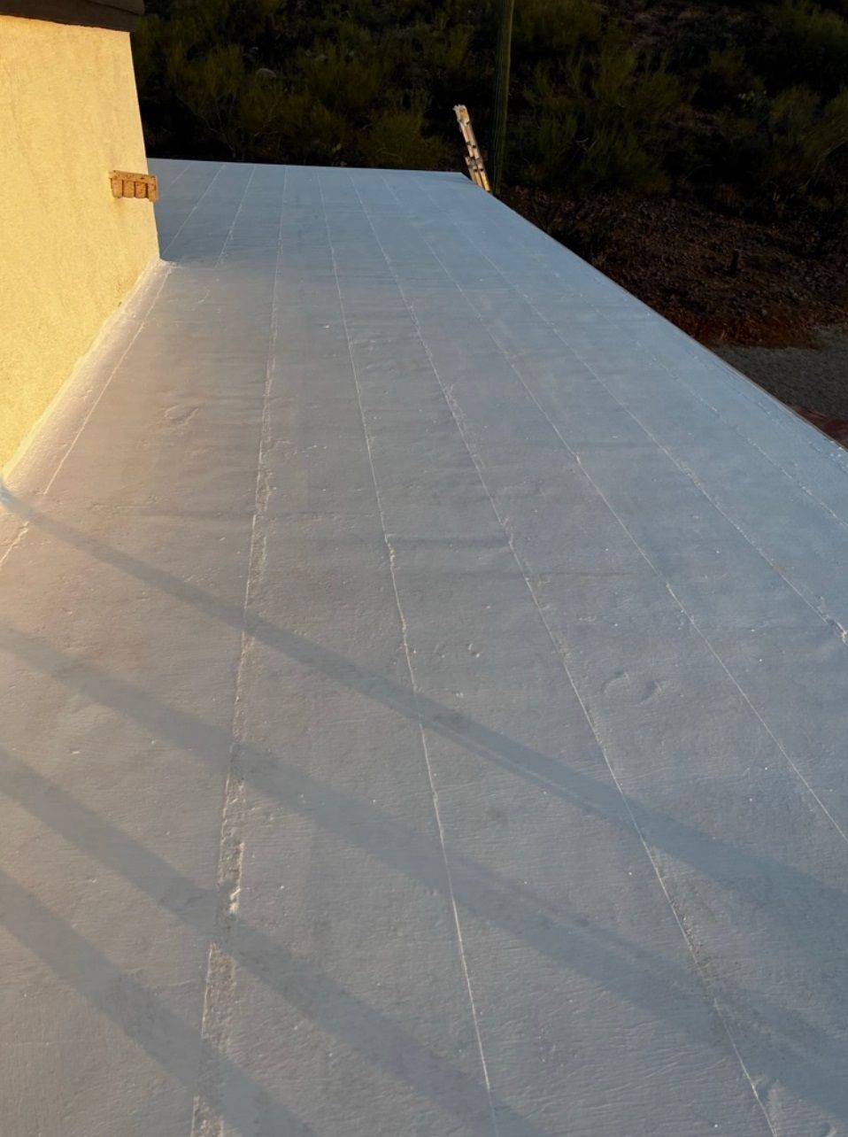 A white roof with a yellow wall in the background.