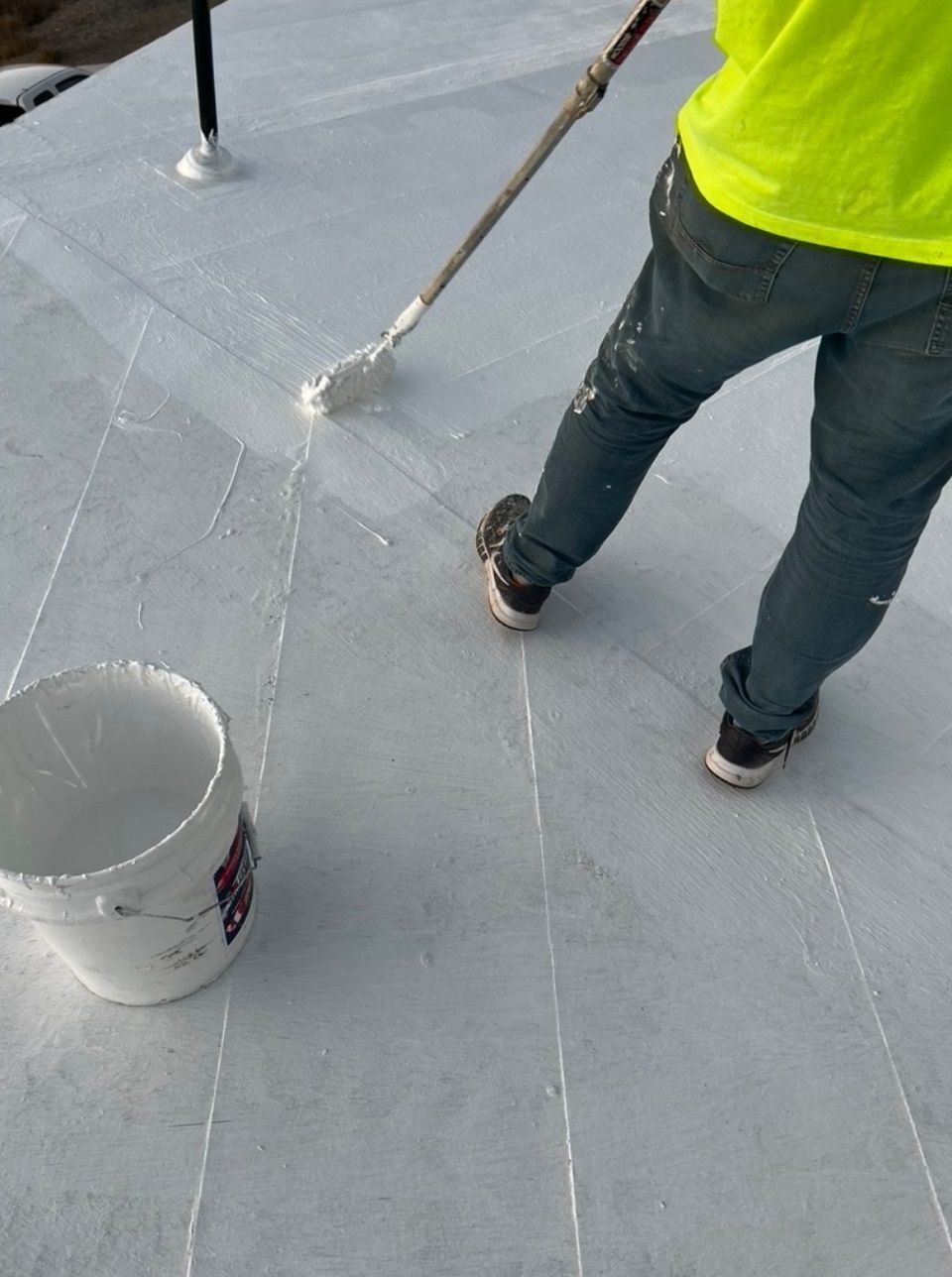 A man is painting a roof with a roller.