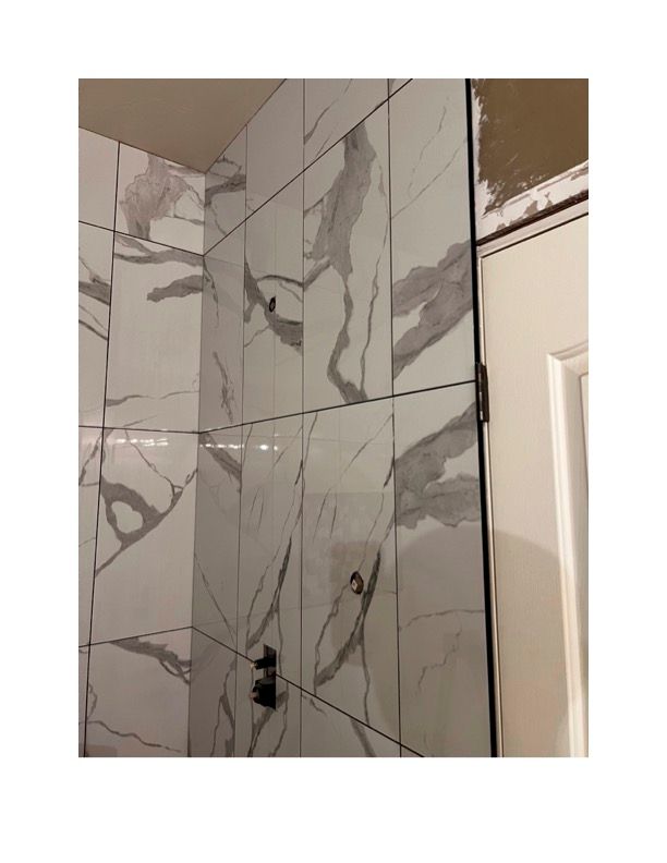 A bathroom with marble tiles on the wall and a door.