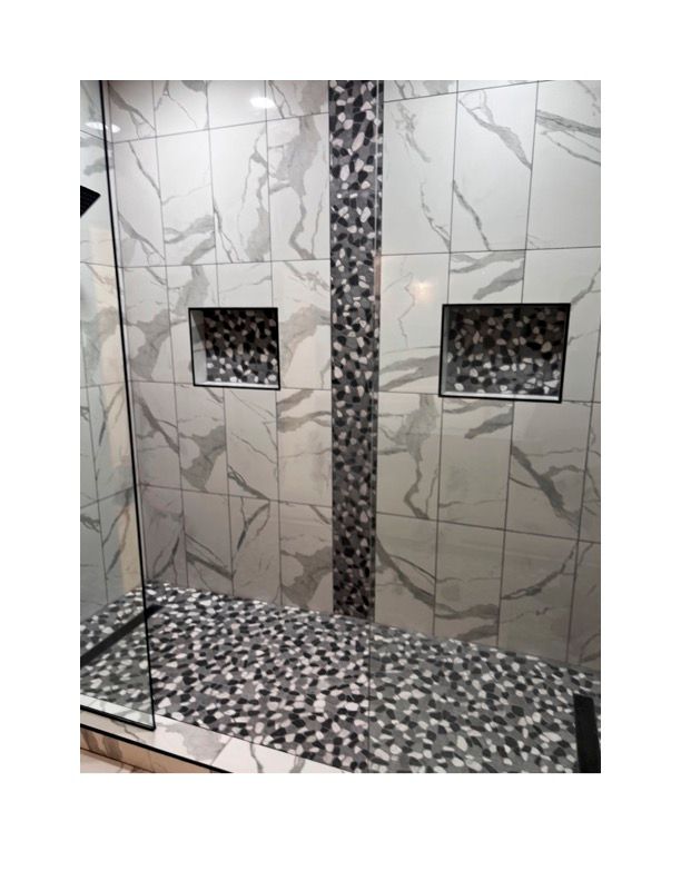 A bathroom with marble tiles and a walk in shower.